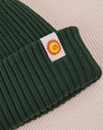 Ribbed Beanie in Swamp Green close up of sun baby tag