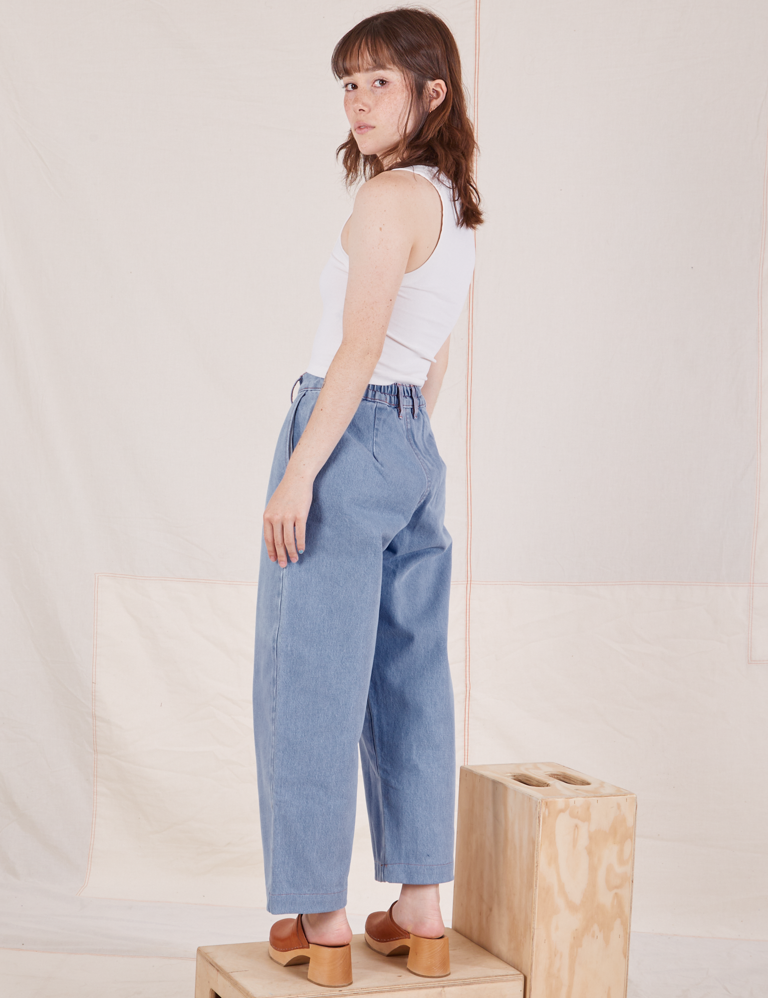 Angled back view of Denim Trouser Jeans in Light Wash and vintage off-white Cropped Tank Top on Hana