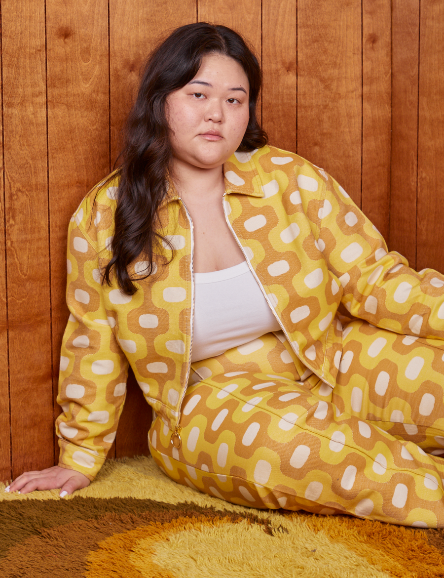 Ashley is sitting on a shaggy rug wearing Jacquard Ricky Jacket in Yellow and matching Western Pants