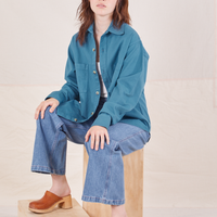 Hana is sitting on a wooden crate wearing Oversize Overshirt in Marine Blue
