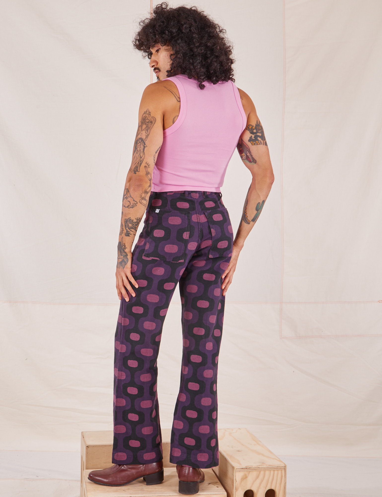 Angled back view of Western Pants in Purple Tile Jacquard and bubblegum pink Cropped Tank Top on Jesse