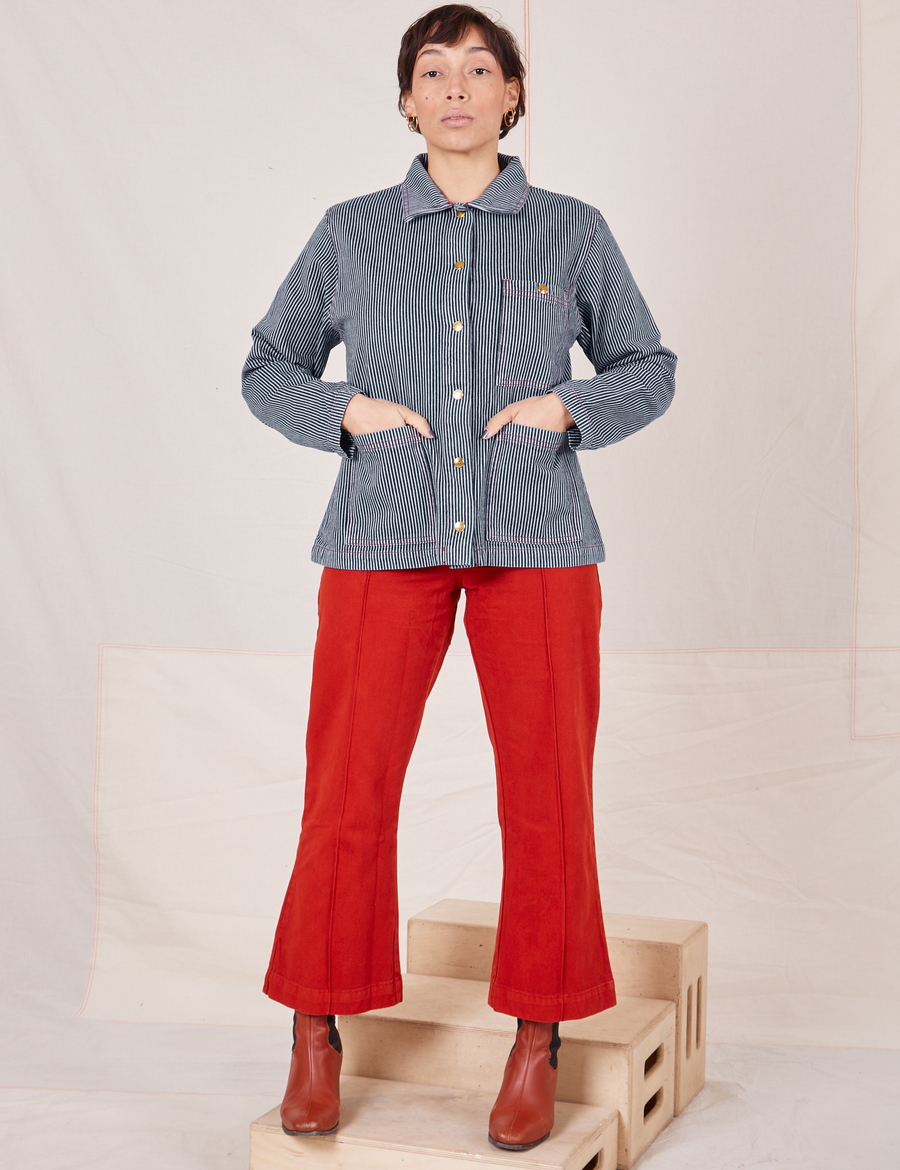 Railroad Stripe Denim Work Jacket and paprika Western Pants worn by Tiara. Jacket is buttoned up and Tiara has her hands in both front pockets