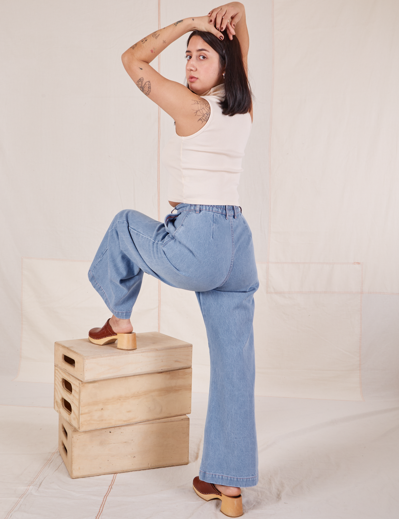 Back view of Indigo Wide Leg Trousers in Light Wash and vintage off-white Sleeveless Turtleneck on Betty