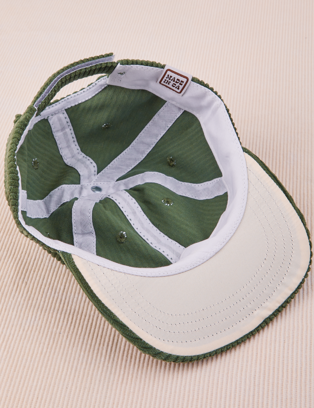 Dugout Corduroy Hat in Emerald Green flipped over. White satin under-bill