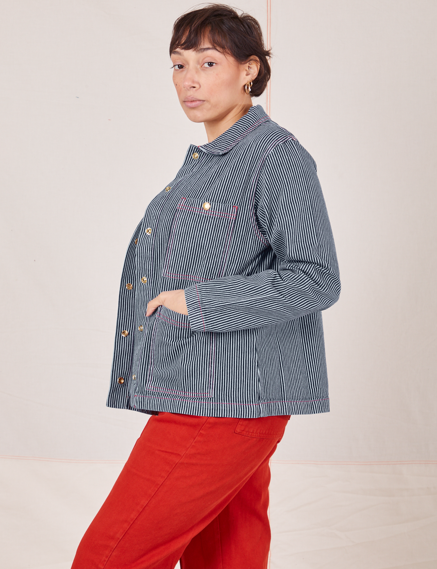 Side view of Railroad Stripe Denim Work Jacket and paprika Western Pants worn by Tiara.
