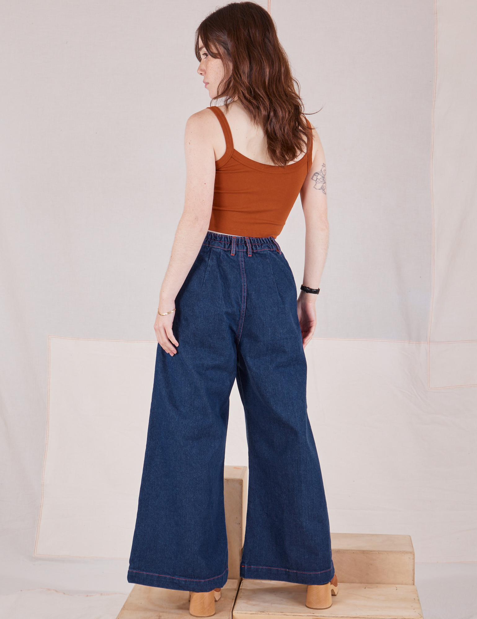 Back view of Indigo Wide Leg Trousers in Dark Wash and burnt terracotta Cropped Cami on Hana
