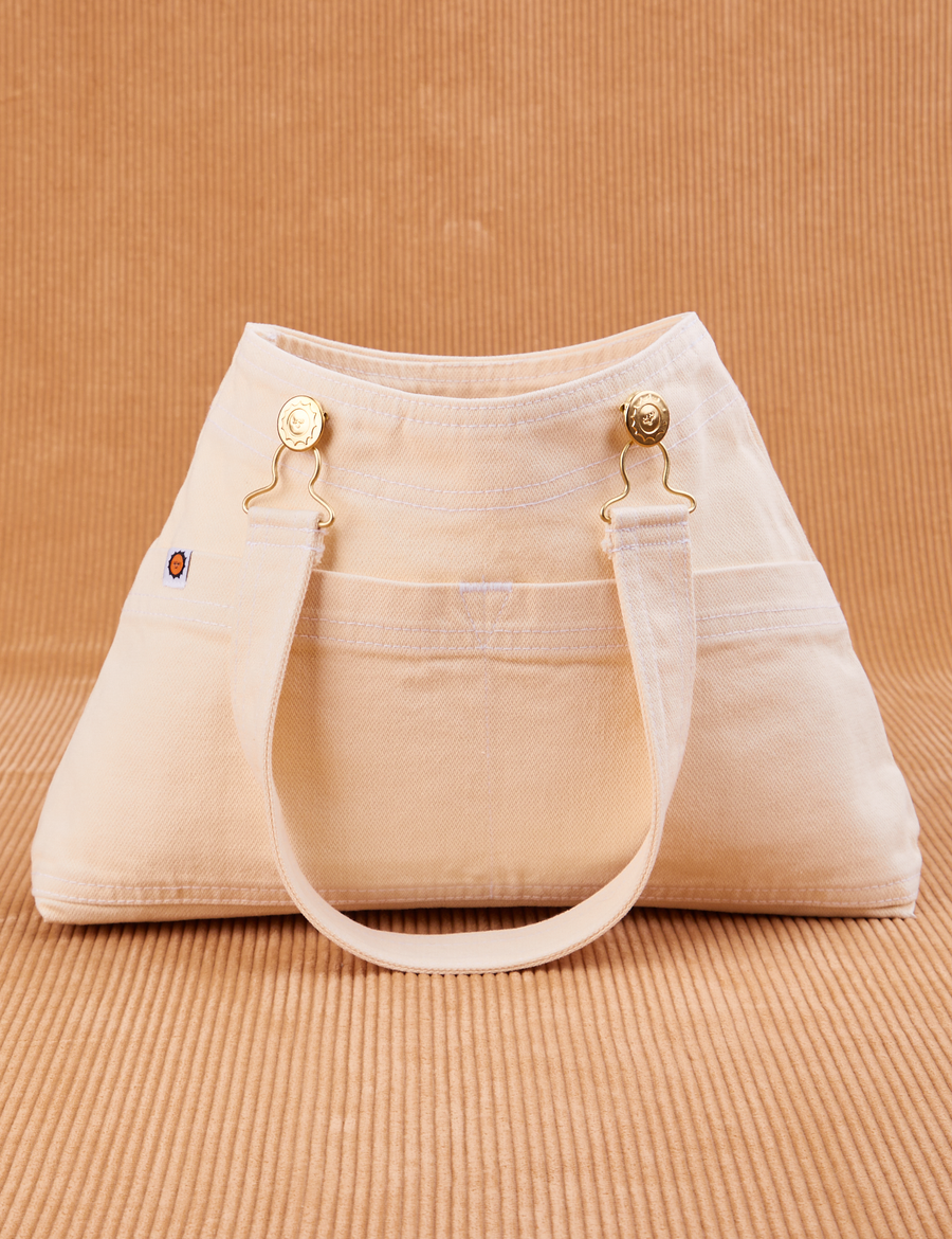 Overall Handbag in Vintage Off-White. Handle strap hanging down front of bag