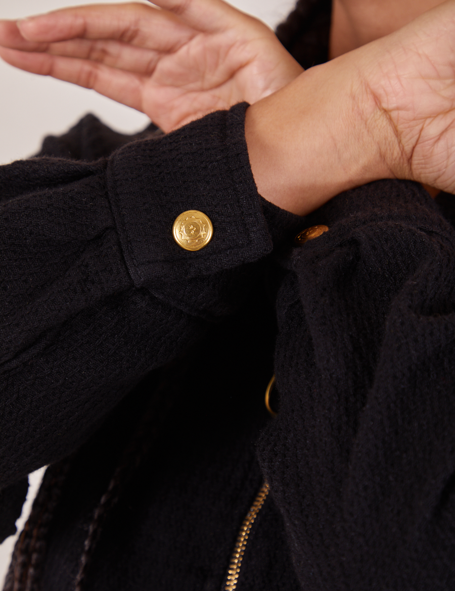 Close up of sleeves of the Ricky Jacket in Basic Black. Custom brass sun baby snap on the cuff of jacket