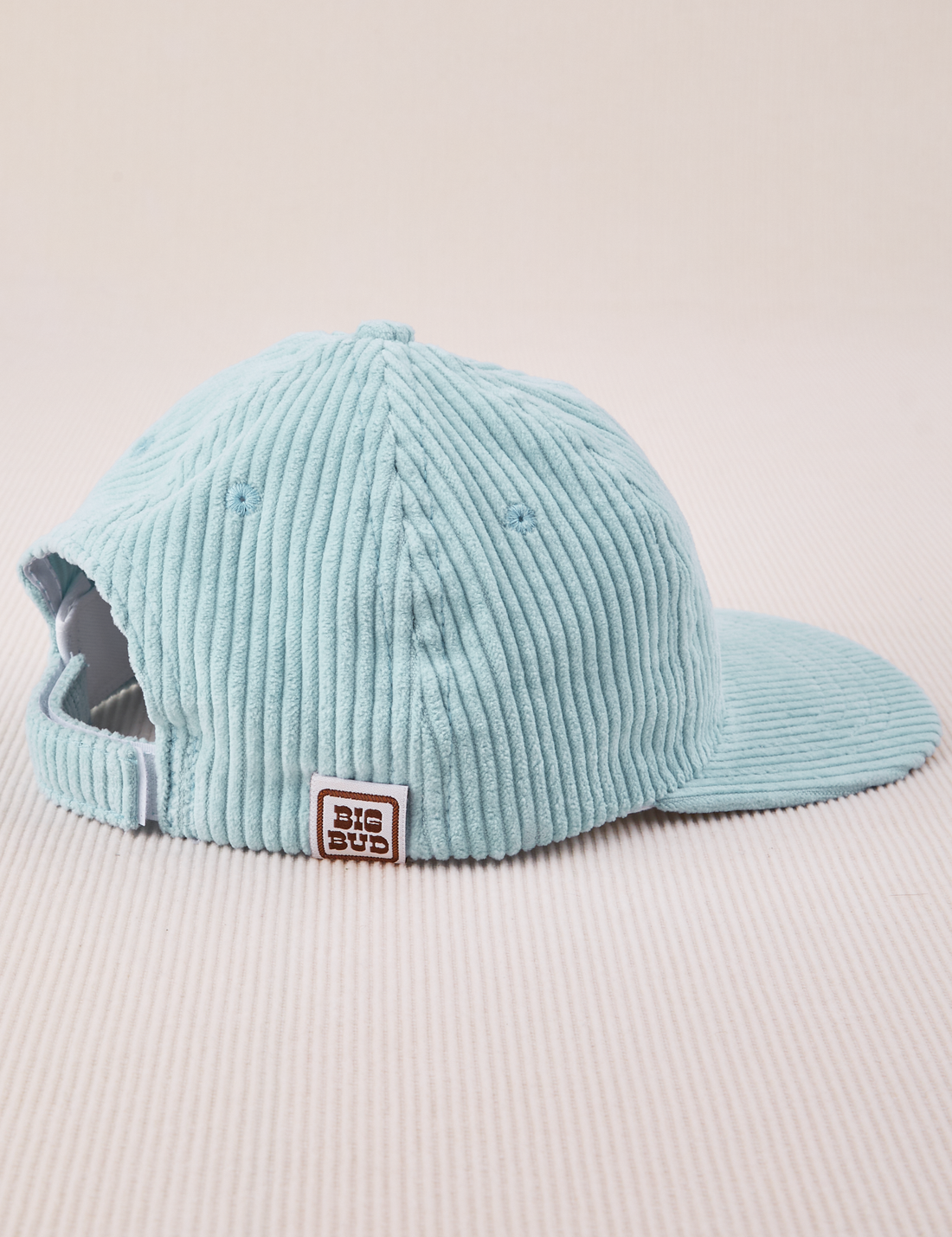 Side view of Dugout Corduroy Hat in Baby Blue. Big Bud label sewn on edge of hat.