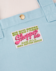 Sun Baby brass snap on Shopper Tote Bag in Baby Blue. Bag label with green and pink text that reads "Big Bud Press Shopper Tote, Made in L.A., 100% Cotton Denim" on white background
