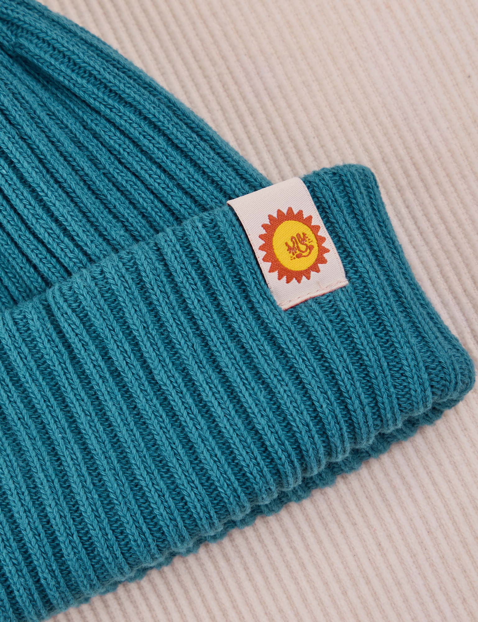 Ribbed Beanie in Marine Blue close up of sun baby tag