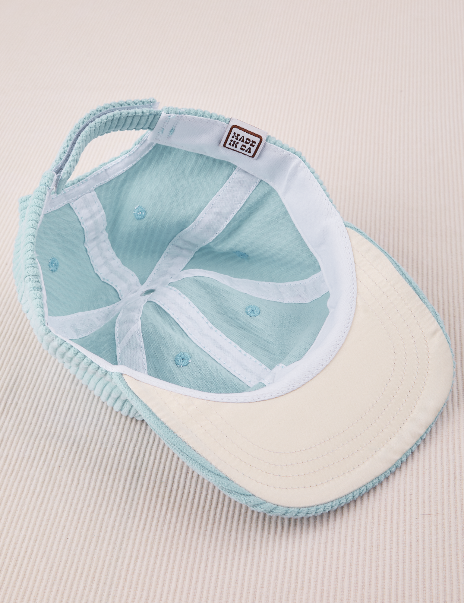 Dugout Corduroy Hat in Baby Blue flipped over. White satin under-bill.