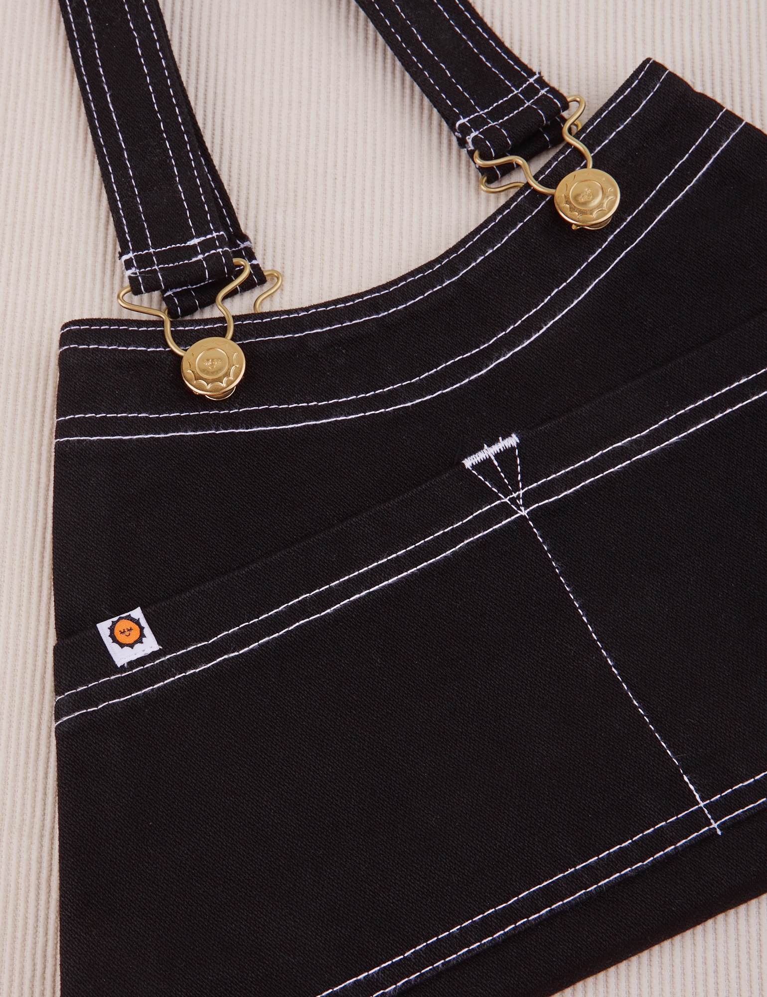 Overall Handbag in Black. White contrast stitching. Brass sun baby buttons and hardware