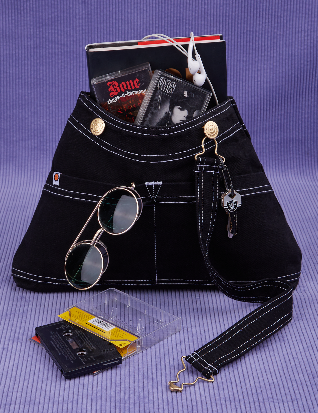 Overall Handbag in Black with book and two cassette tapes in main compartment. Keys hanging from brass hardware in the front. Sunglasses in the front pocket.