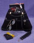 Overall Handbag in Black with book and two cassette tapes in main compartment. Keys hanging from brass hardware in the front. Sunglasses in the front pocket.
