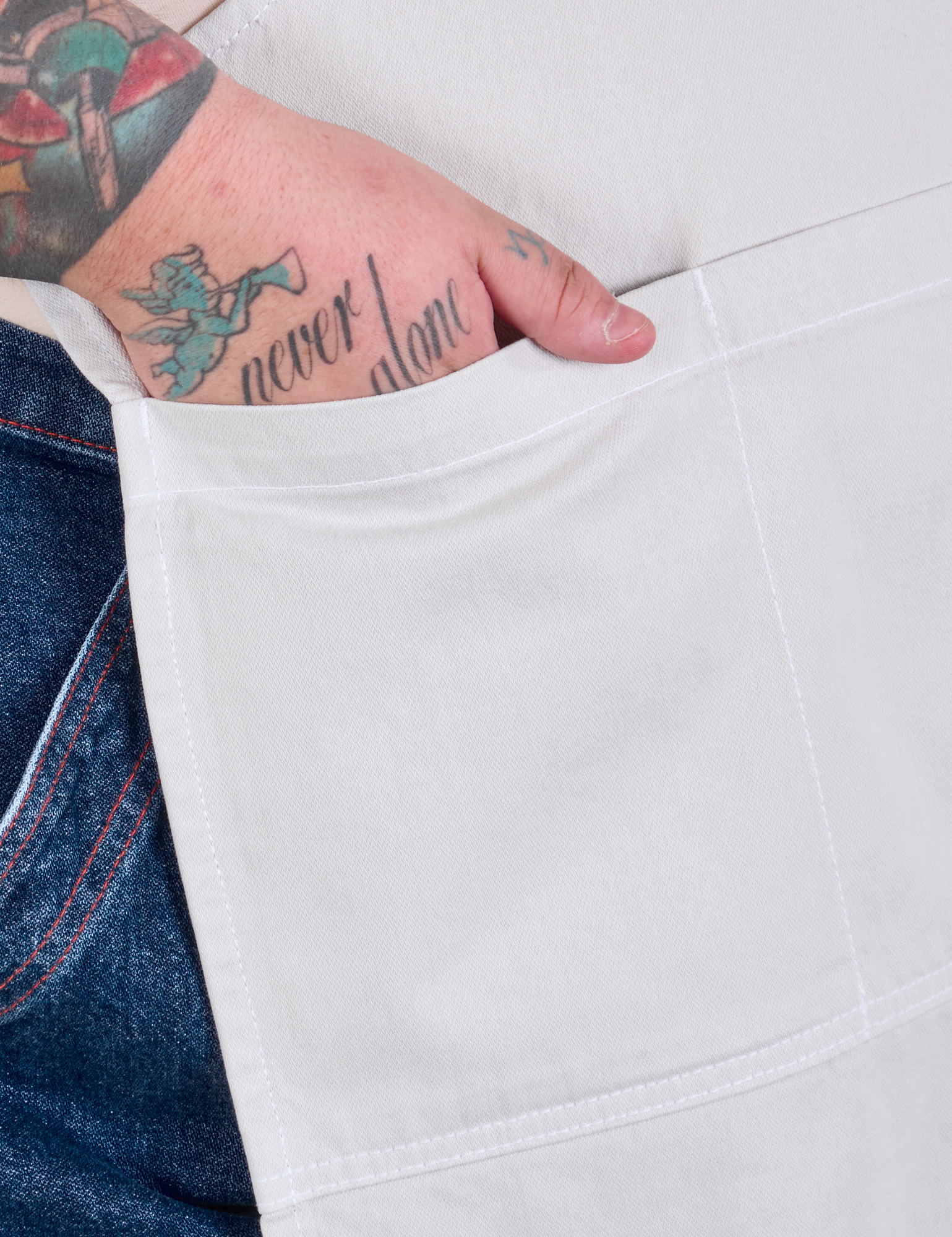 Close up of Sam&#39;s hand in the pocket of a Full Denim Apron in Stone White