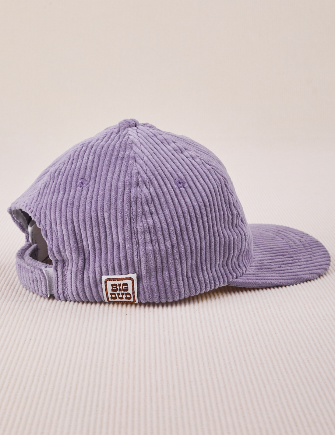Side view of Dugout Corduroy Hat in Faded Grape. Big Bud label sewn on edge of hat.