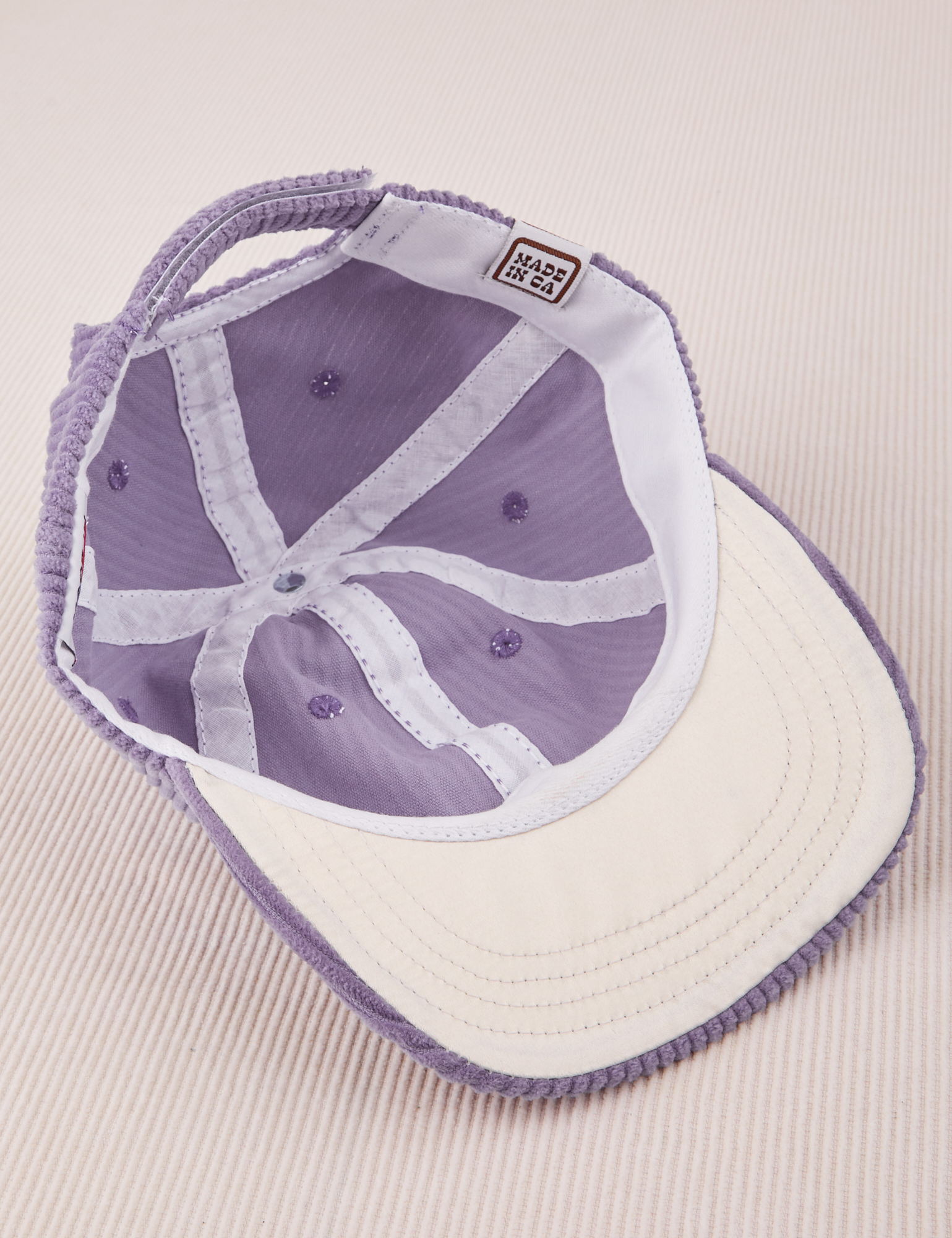 Dugout Corduroy Hat in Fade Grape flipped over. White satin under-bill