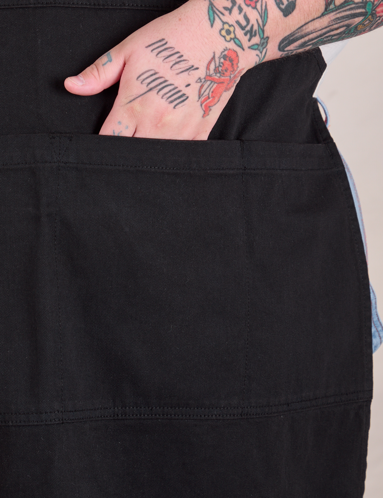 Close up of Sam&#39;s hand in the pocket of the Full Denim Apron in Basic Black