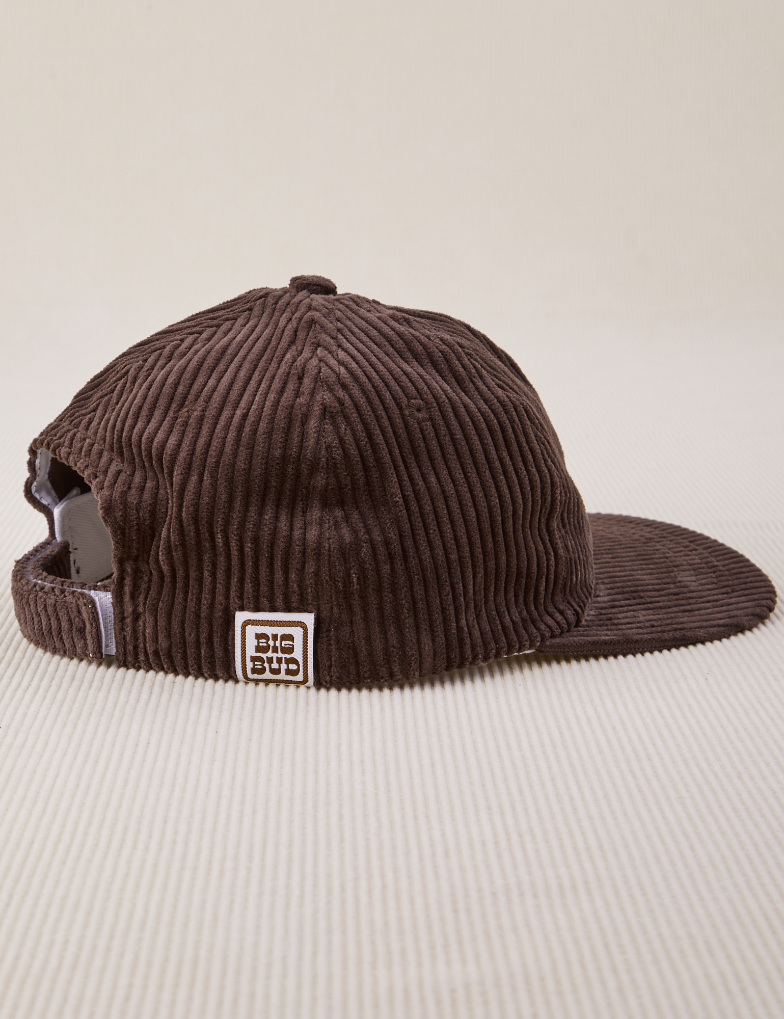 Side view of Dugout Corduroy Hat in Espresso Brown. Big Bud label sewn on edge of hat.