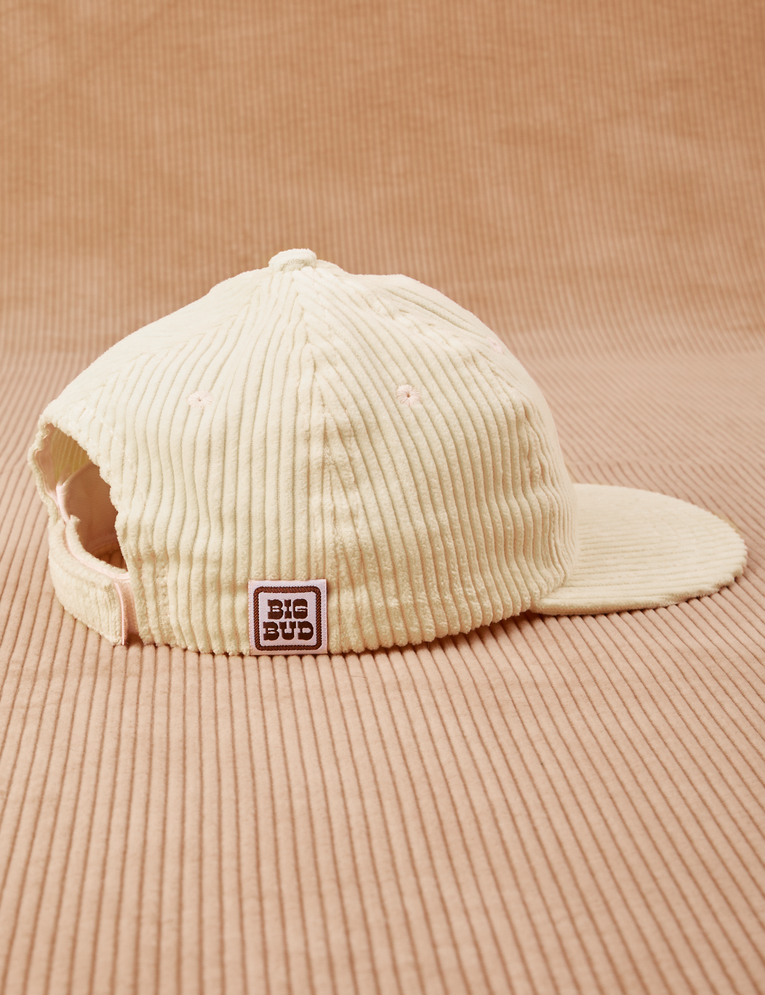 Side view of Dugout Corduroy Hat in Vintage Off-White. Big Bud label sewn onto edge of hat.