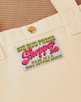 Sun Baby brass snap on Shopper Tote Bag in Vintage Off-White. Bag label with green and pink text that reads "Big Bud Press Shopper Tote, Made in L.A., 100% Cotton Denim" on a white background