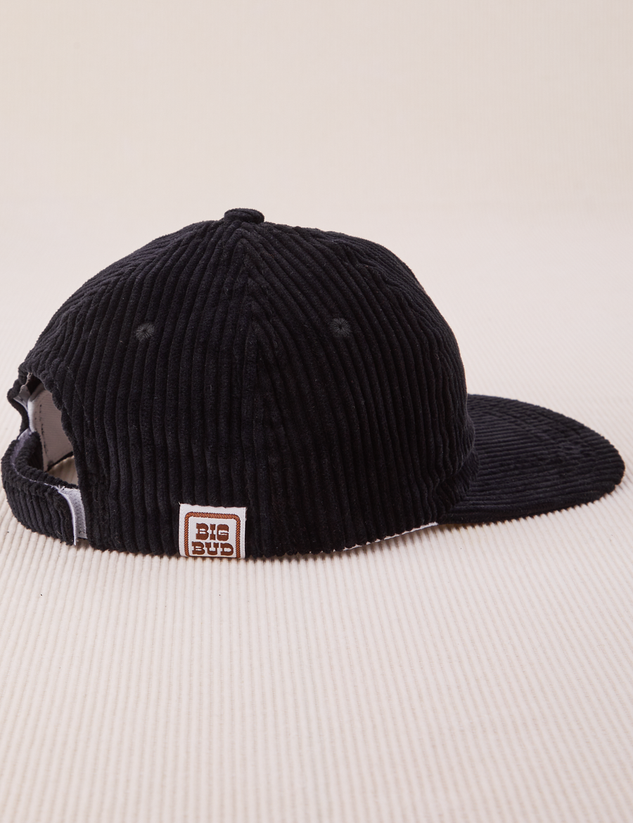 Side view of Dugout Corduroy Hat in Black. Big Bud label sewn on edge of hat.