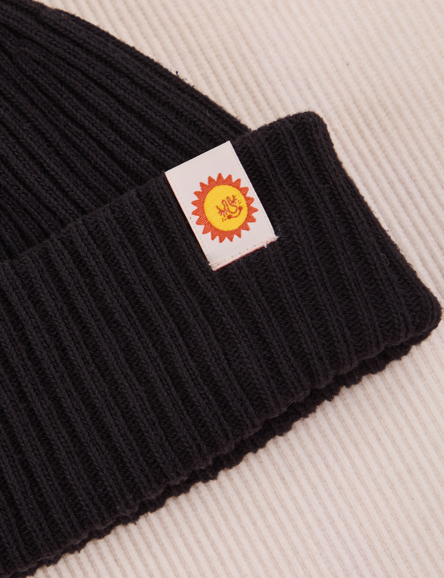 Ribbed Beanie in Basic Black close up of sun baby tag