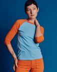 Alex is 5'8" and wearing P Baby Blue/Orange Colorblock Raglan Tee
