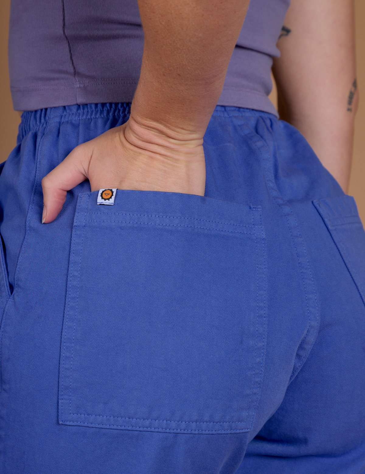 Close up of Alex's hand in the back pocket wearing the Cornflower Blue Action Pant