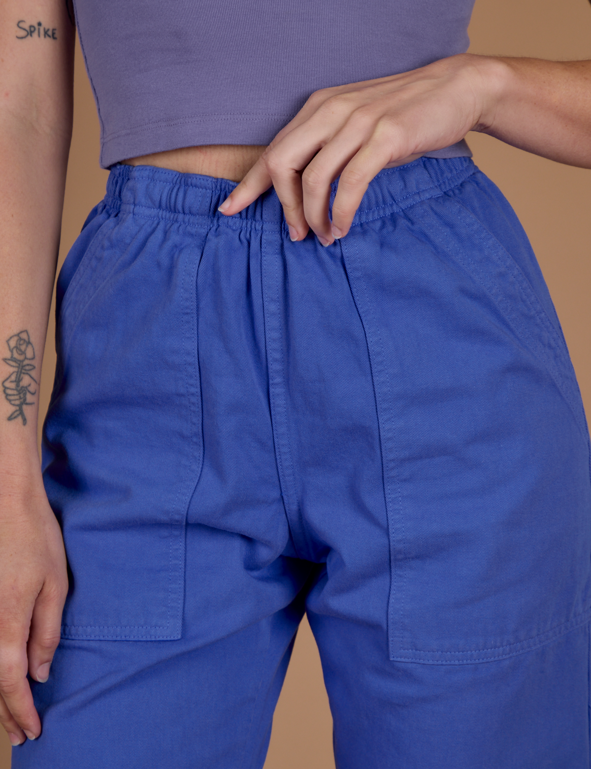 Close up of Alex's hand on the waistband of the Cornflower Blue Action Pant
