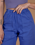 Close up of Alex's hand on the waistband of the Cornflower Blue Action Pant