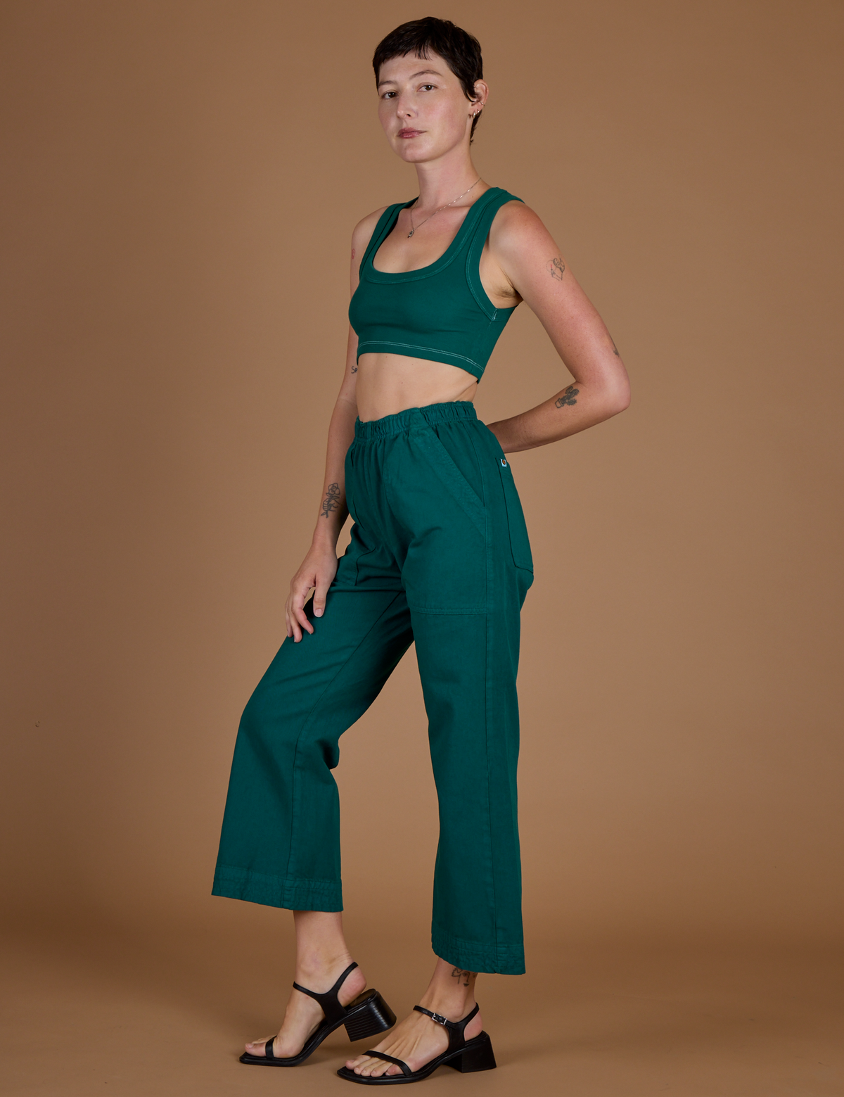 Angled side view of Alex in the Hunter Green Action Pant
