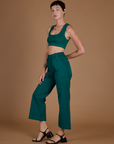 Angled side view of Alex in the Hunter Green Action Pant