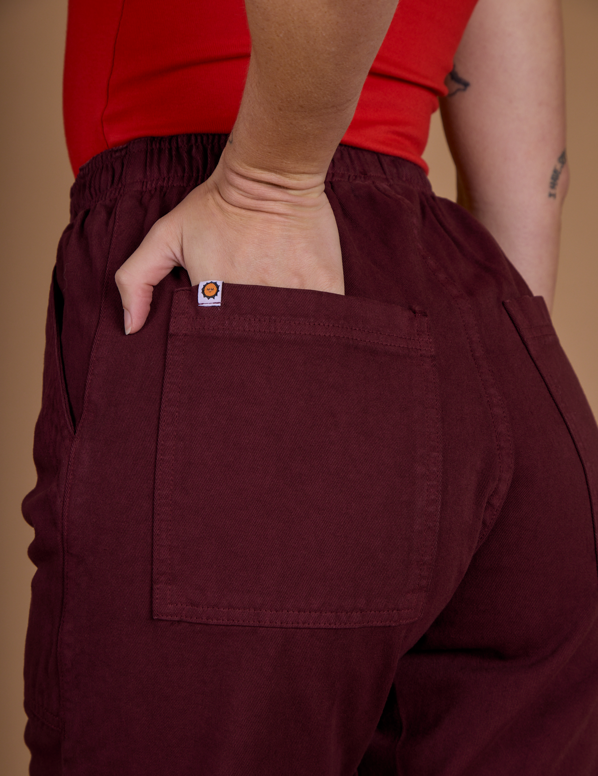 Close up of Alex's hand in the back pocket of the Red Wine Action Pant