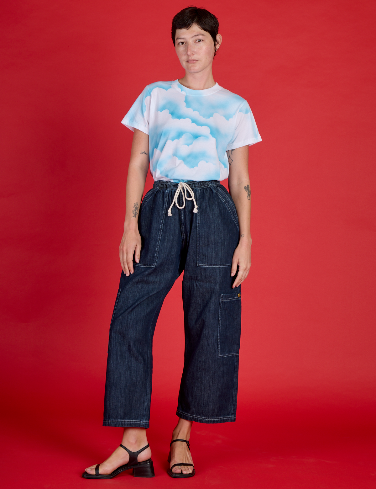 Alex wearing the Cloud Coverage Airbrush Vintage Tee tucked into the Dark Wash Denim Drop Pocket Pants