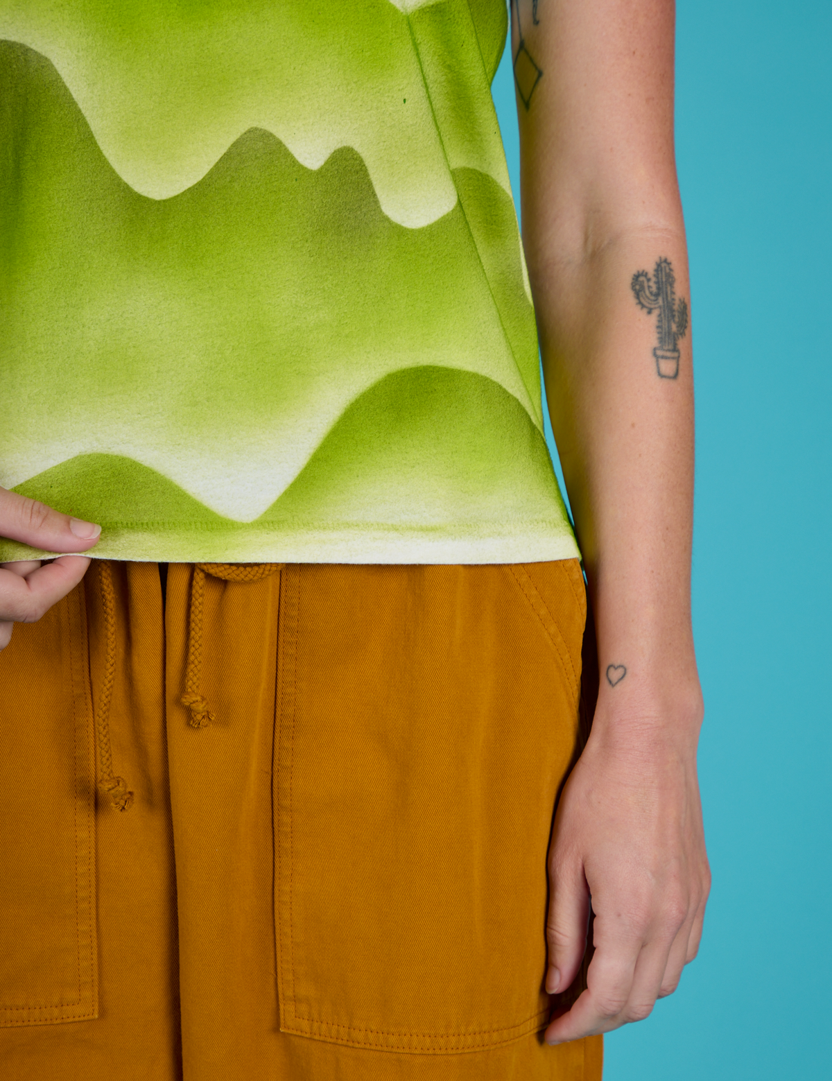 Close up of the Green Hills Airbrush Vintage Tee's hemline worn by Alex