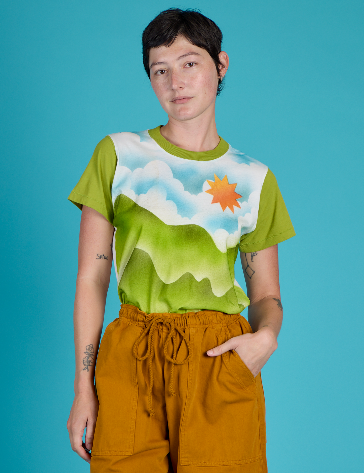 Alex is wearing the Green Hills Airbrush Vintage Tee tucked into the Spicy Mustard Drop Pocket Pants