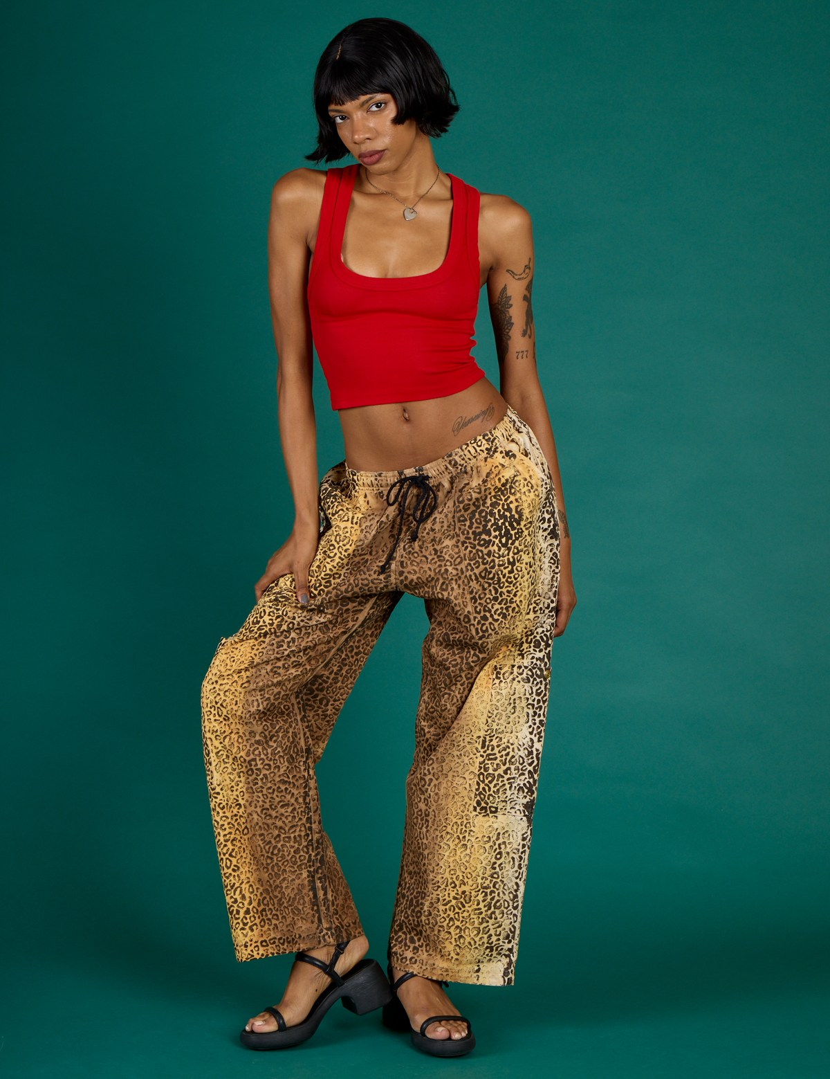 Kira is 5'10" and wearing XS Leopard Drop Pocket Pants with the Mustang Red Cropped Tank