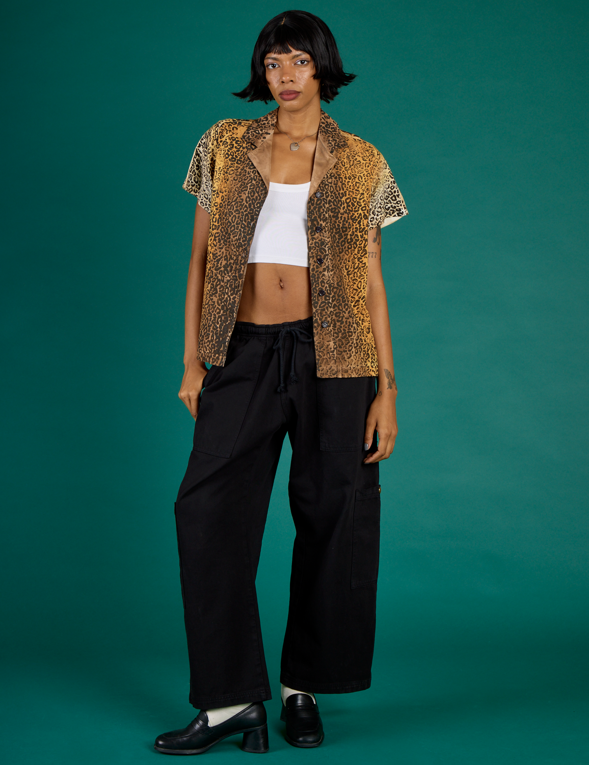 Kira is 5'10" and wearing XXS Leopard Pantry Button Up with the Black Drop Pocket Pants