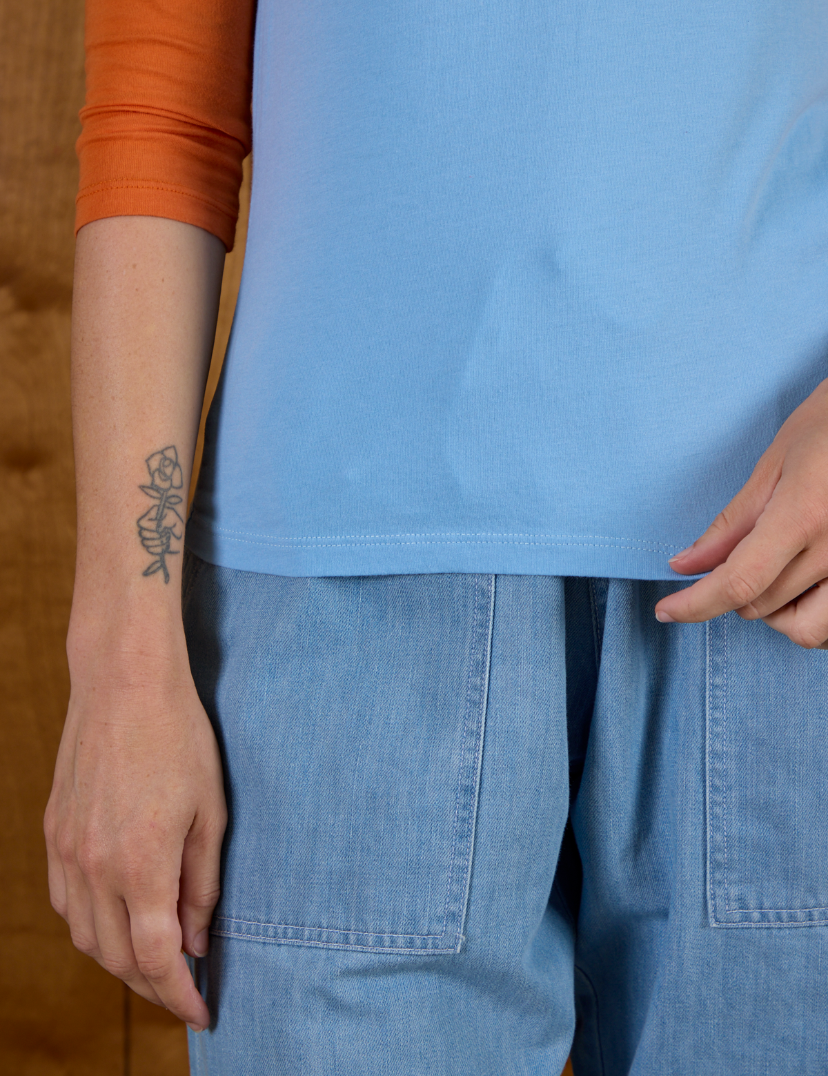 Close up of hem on the Baby Blue/Orange Colorblock Raglan Tee worn by Alex