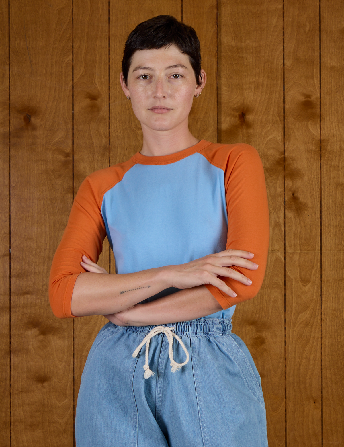 Alex is wearing the Baby Blue/Orange Colorblock Raglan Tee