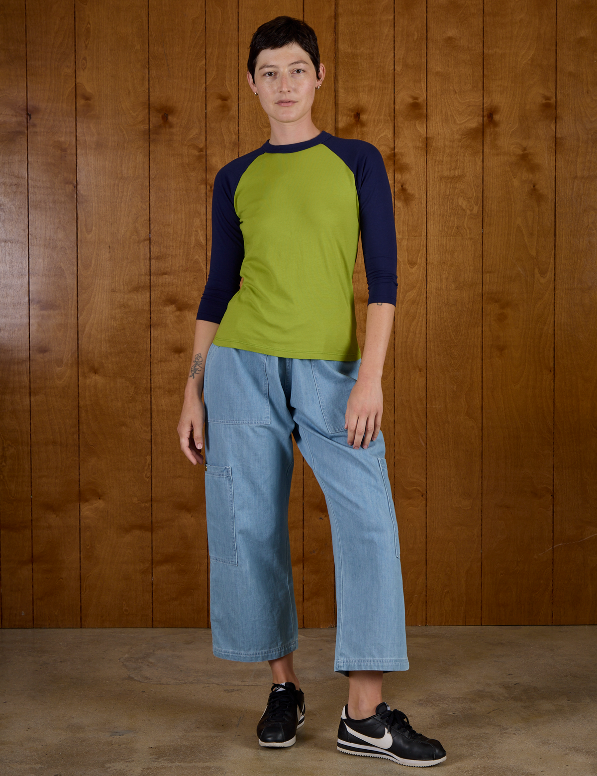 Alex is wearing the Gross Green/Navy Colorblock Raglan Tee with the Light Wash Denim Drop Pocket Pants