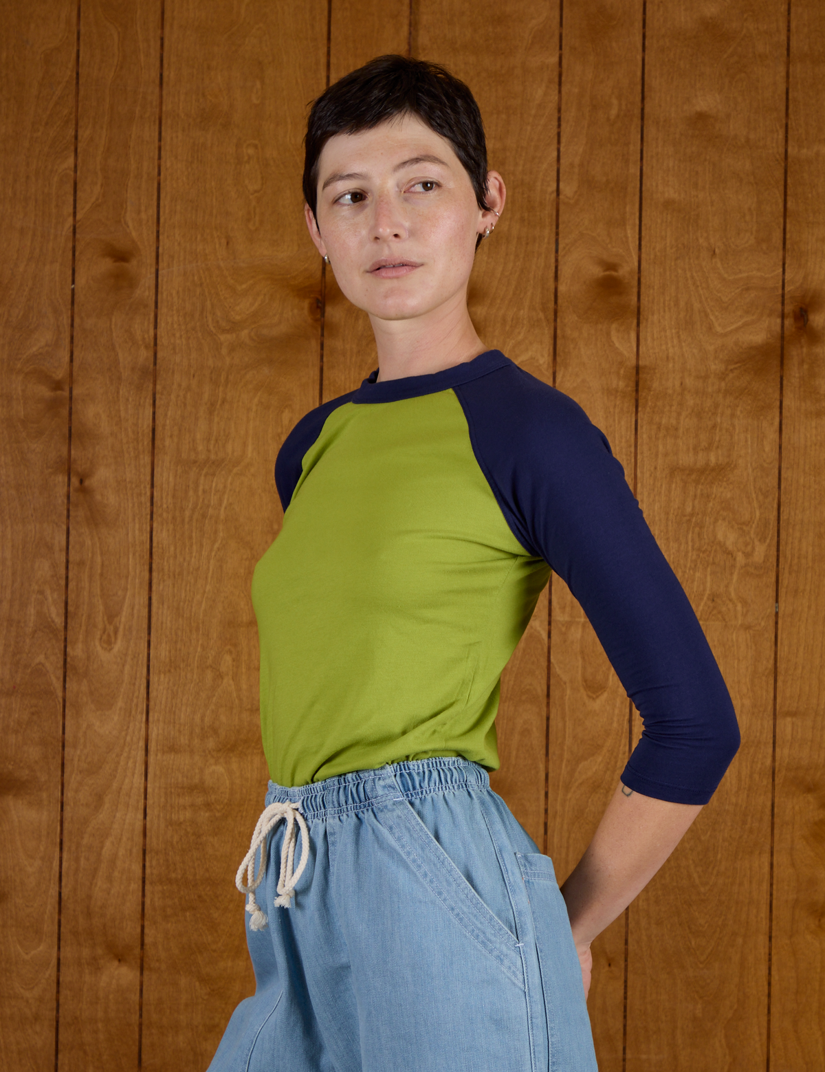 Angled side view of the Gross Green/Navy Colorblock Raglan Tee on Alex