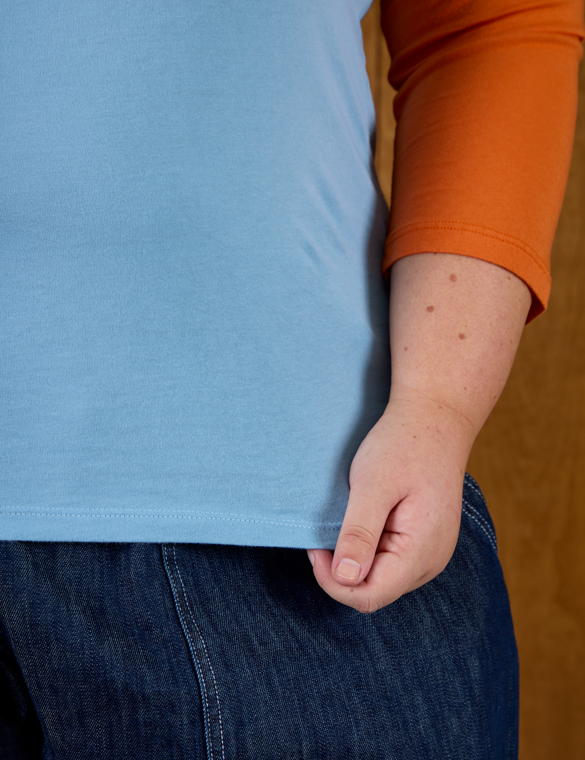 Close up of hem on the Baby Blue/Orange Colorblock Raglan Tee worn by Juliet