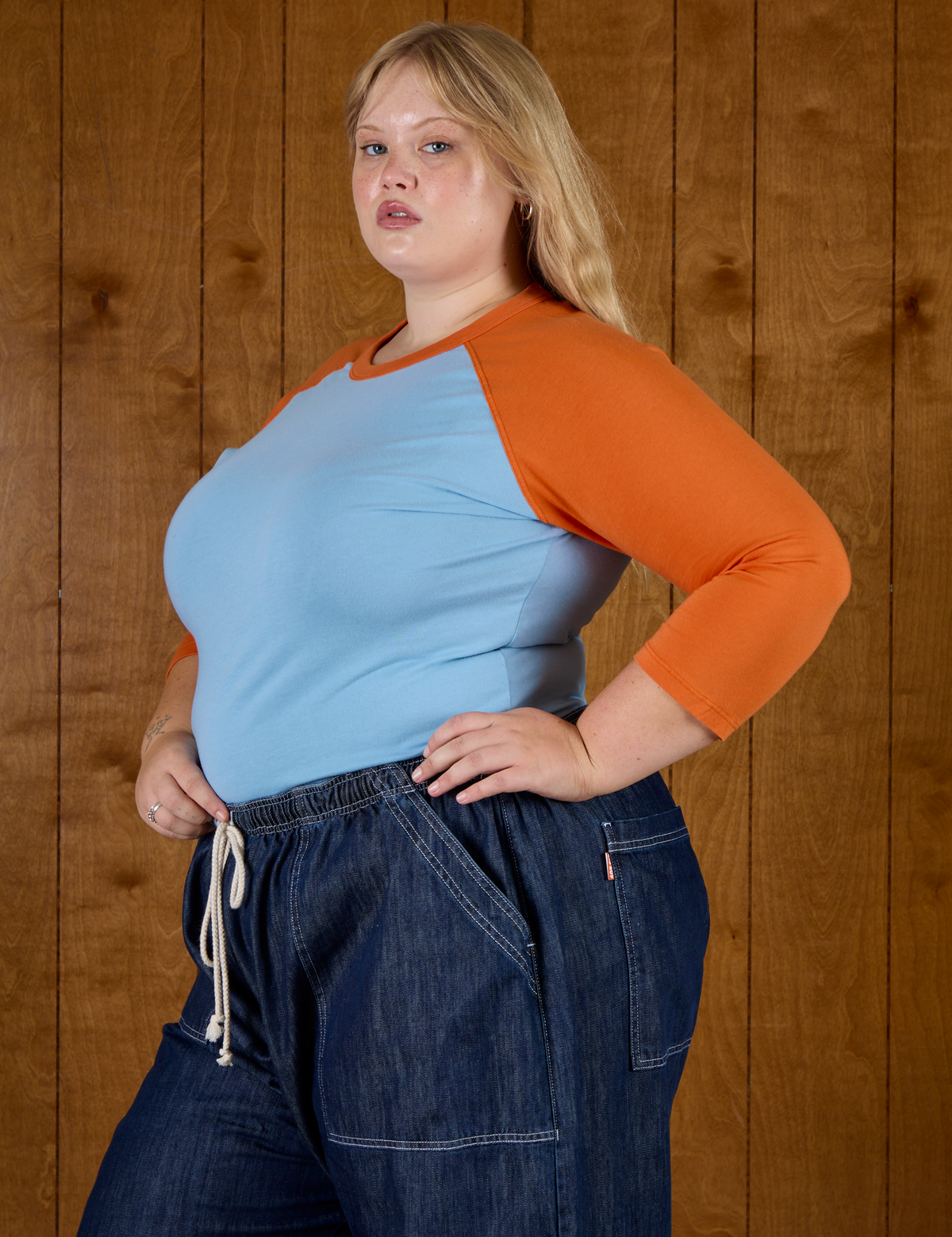 Angled side view of Juliet wearing the Baby Blue/Orange Colorblock Raglan Tee
