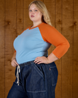 Angled side view of Juliet wearing the Baby Blue/Orange Colorblock Raglan Tee