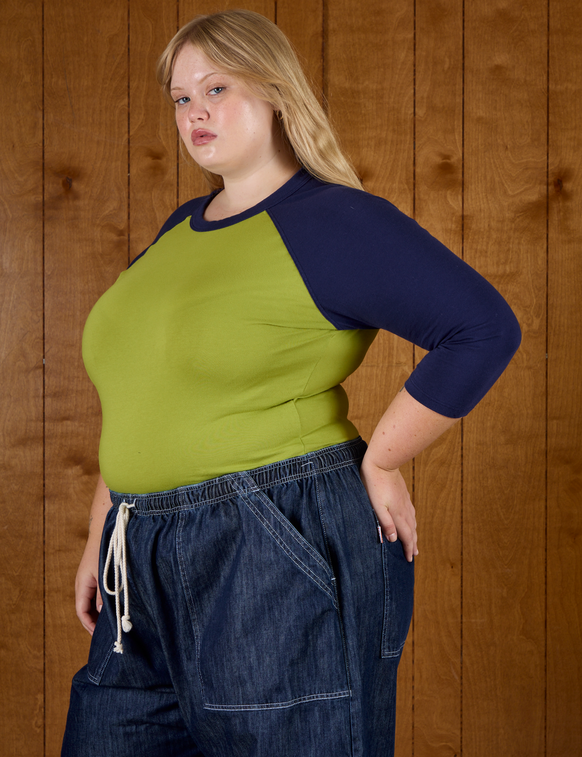 Angled side view of Juliet wearing the Gross Green/Navy Colorblock Raglan Tee