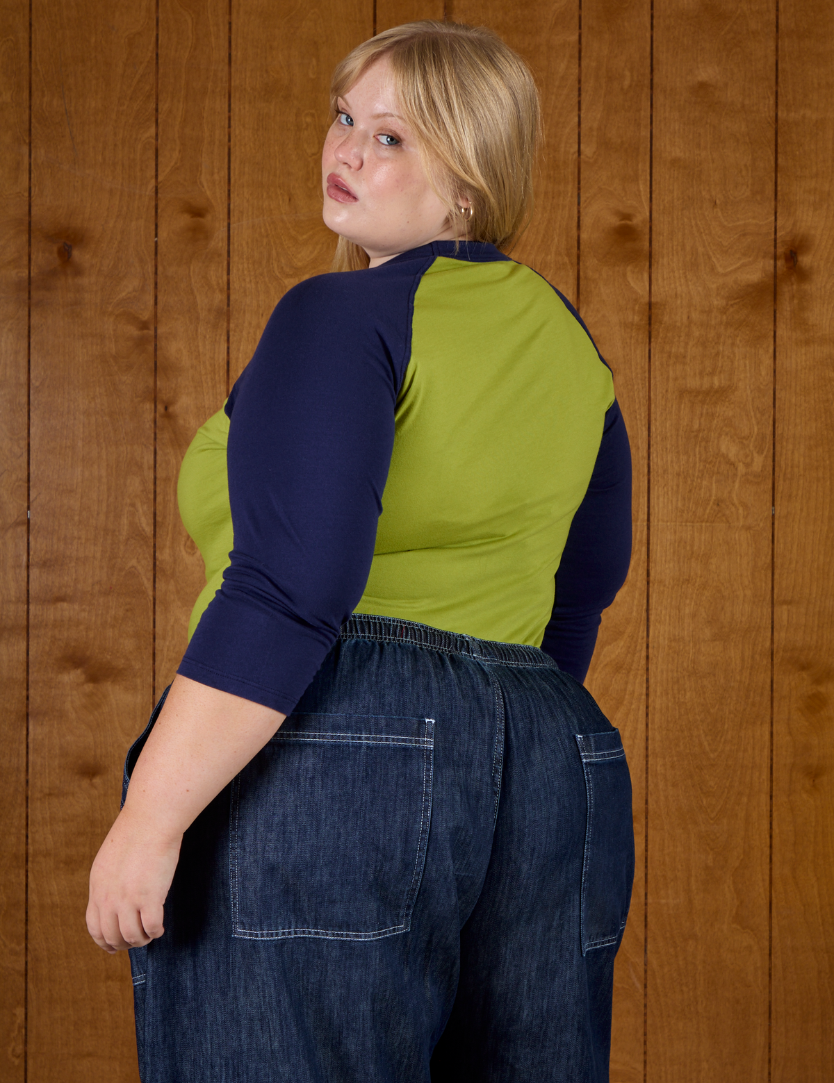 Angled back view of Juliet in the Gross Green/Navy Colorblock Raglan Tee