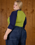 Angled back view of Juliet in the Gross Green/Navy Colorblock Raglan Tee